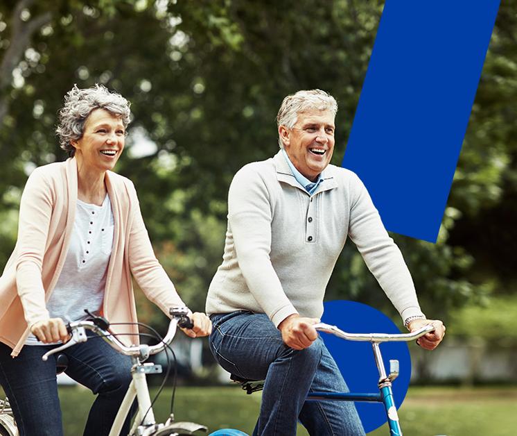 Pareja de adultos mayores montando bicicleta felices en el parque