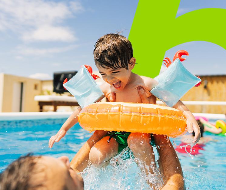 Padre cargando a su hijo feliz en una piscina 