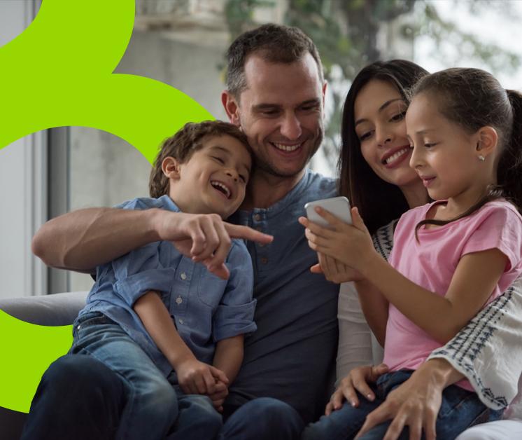 Familia de cuatro integrantes sonriendo sentados en un sofá