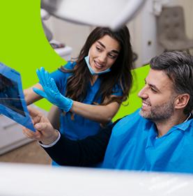 Doctora con un paciente en consultorio explicando radiografía de sus dientes 