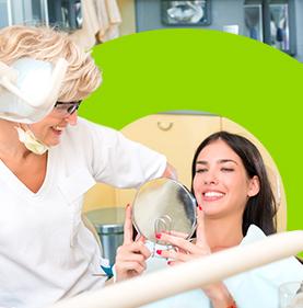 Mujer sonriente viendo su nueva sonrisa junto a su doctora 