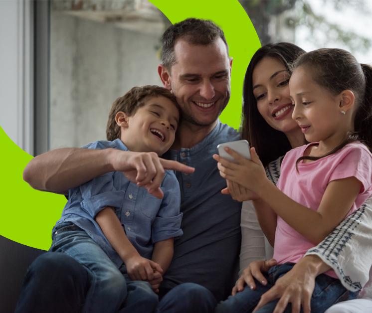 Familia de cuatro integrantes sonriendo sentados en un sofá