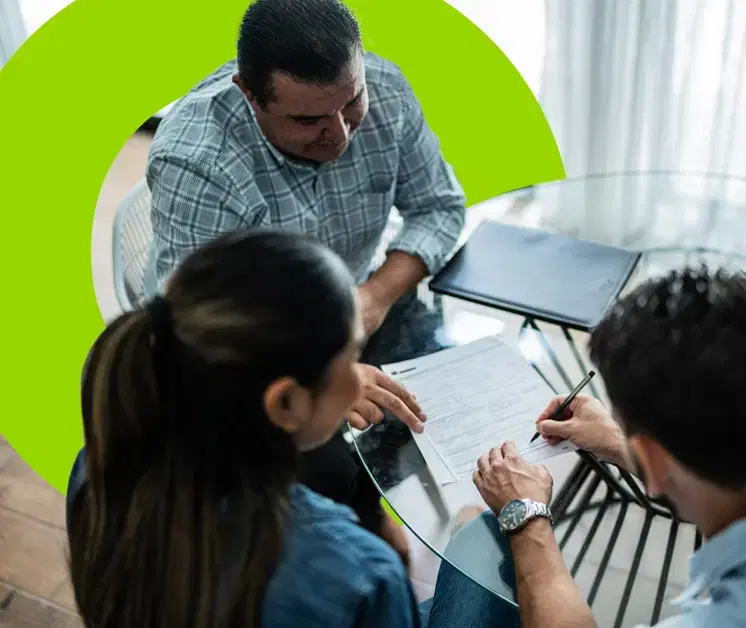 Personas reunidas en una mesa firmando documentos